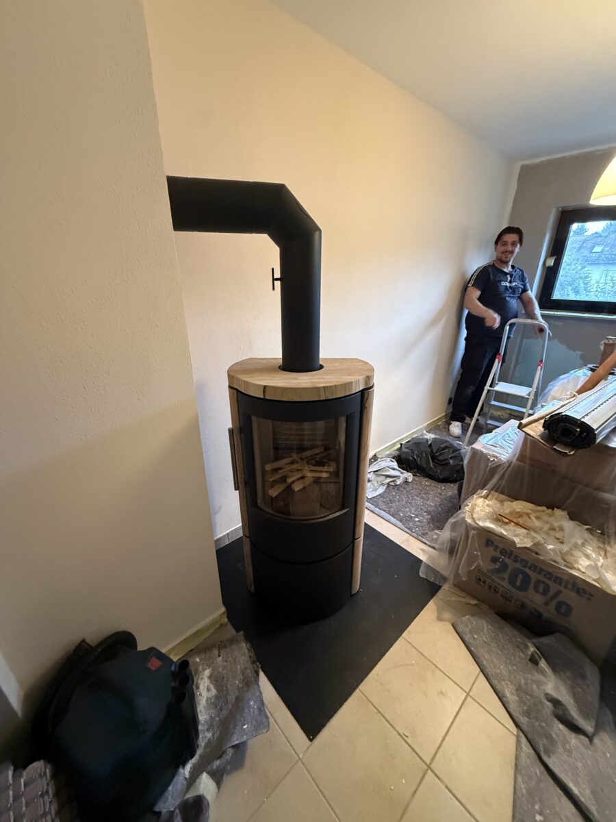 Runder Kaminofen mit heller Steinabdeckung bei der Montage